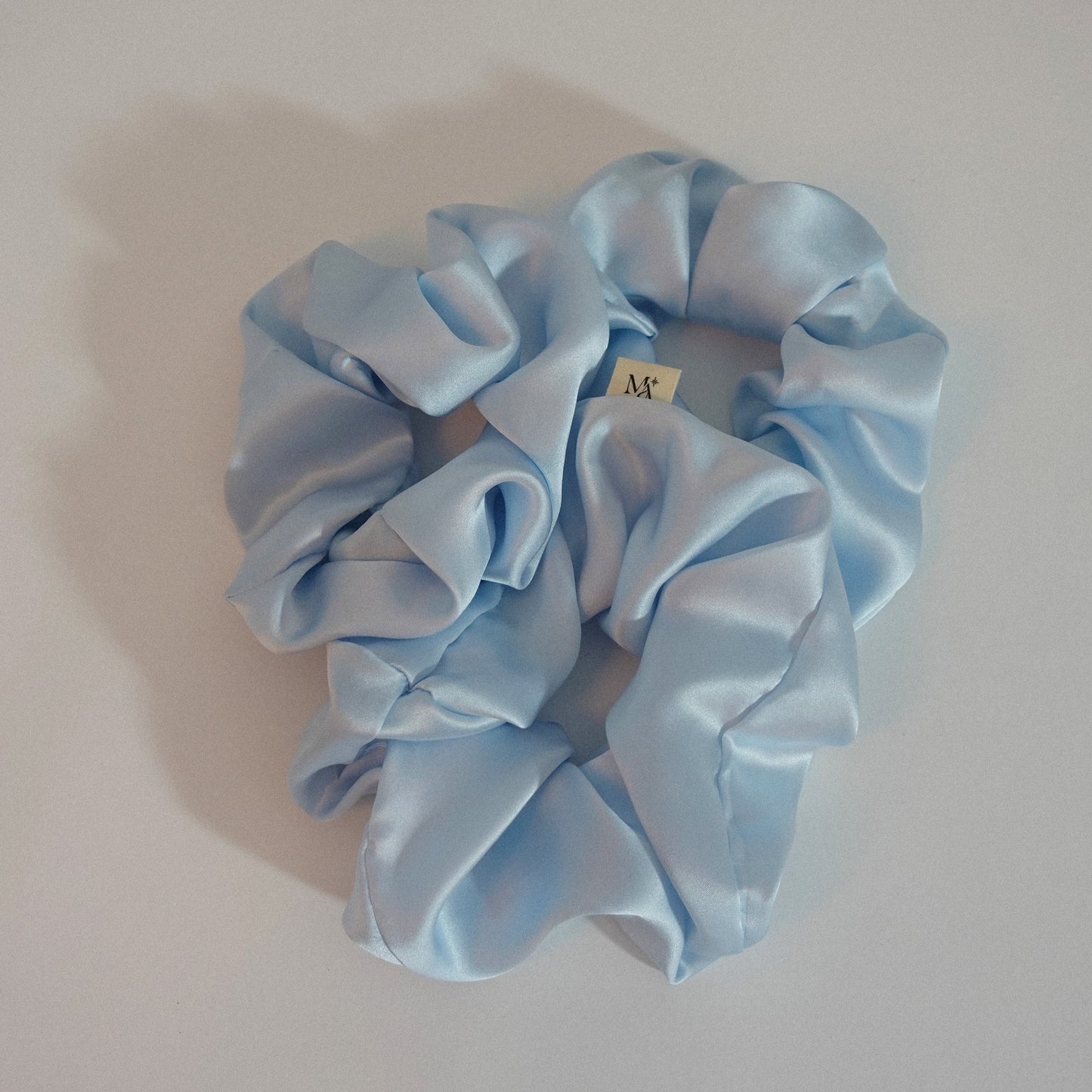 Light blue silk scrunchies on a white background