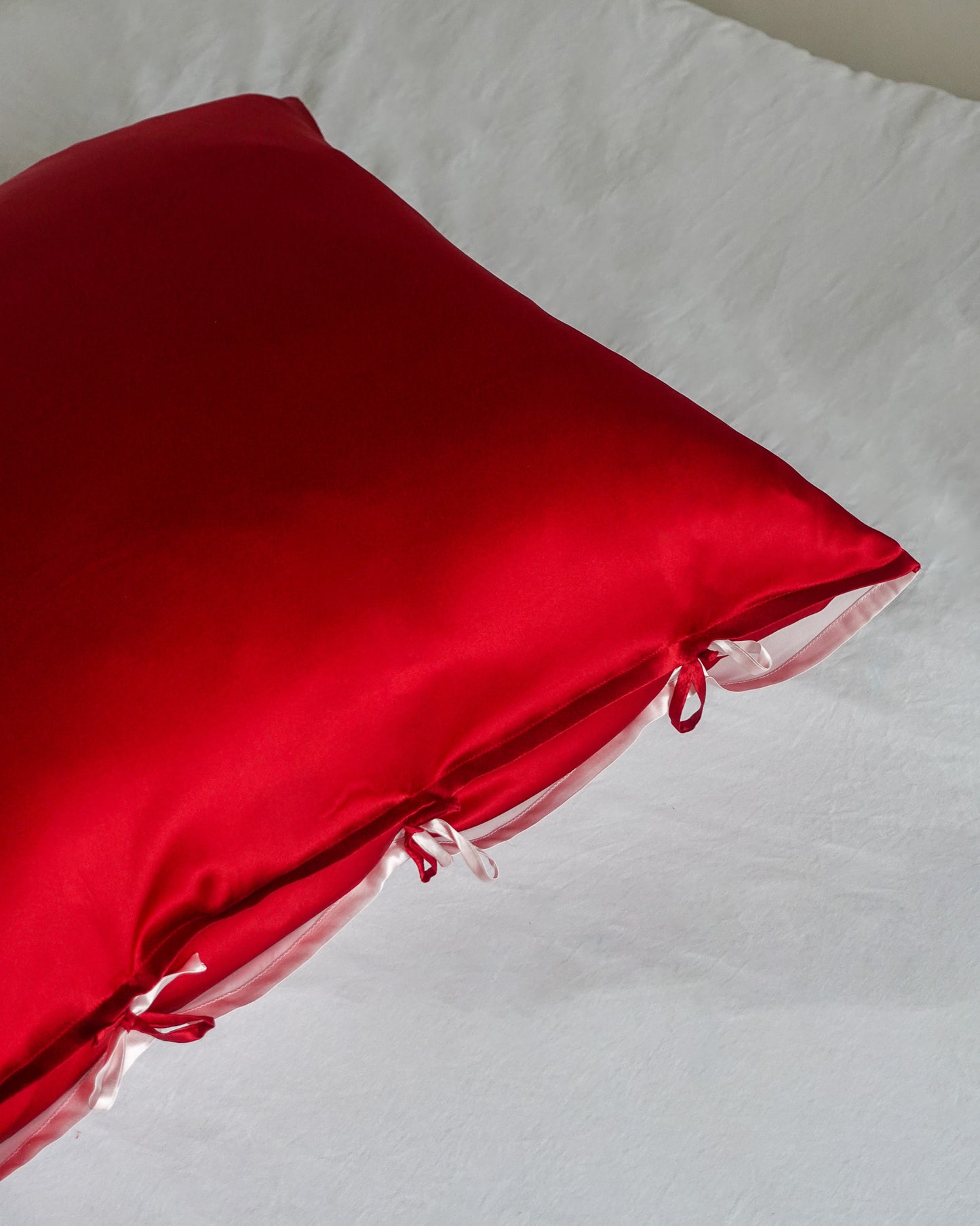 red and pink reversible silk pillowcase on a white sheet