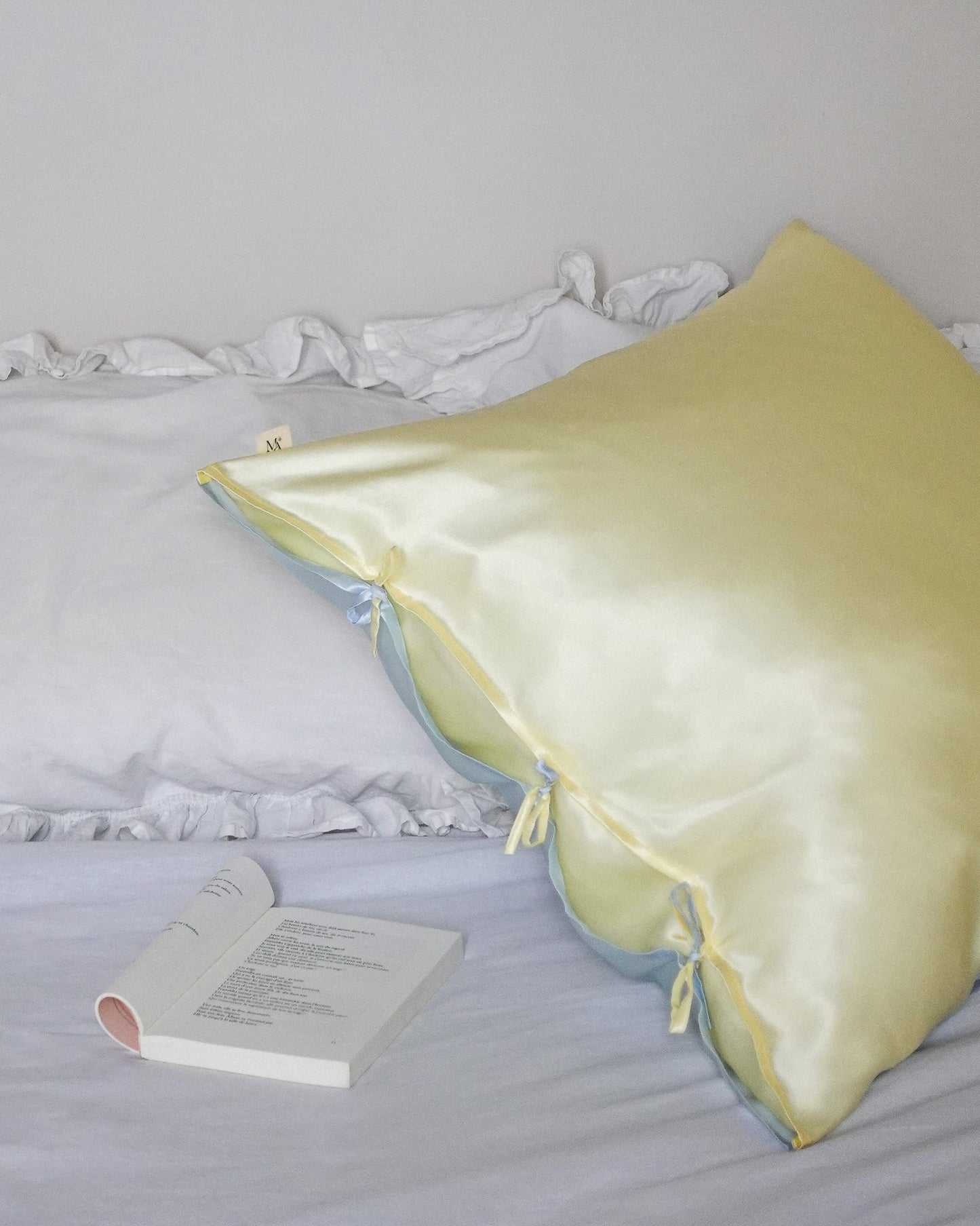 blue and yellow mulberry silk pillowcase on a bed next to a book