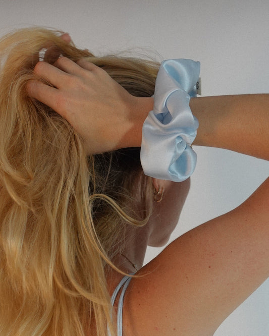 Woman wearing a light blue silk scrunchie on her wrist