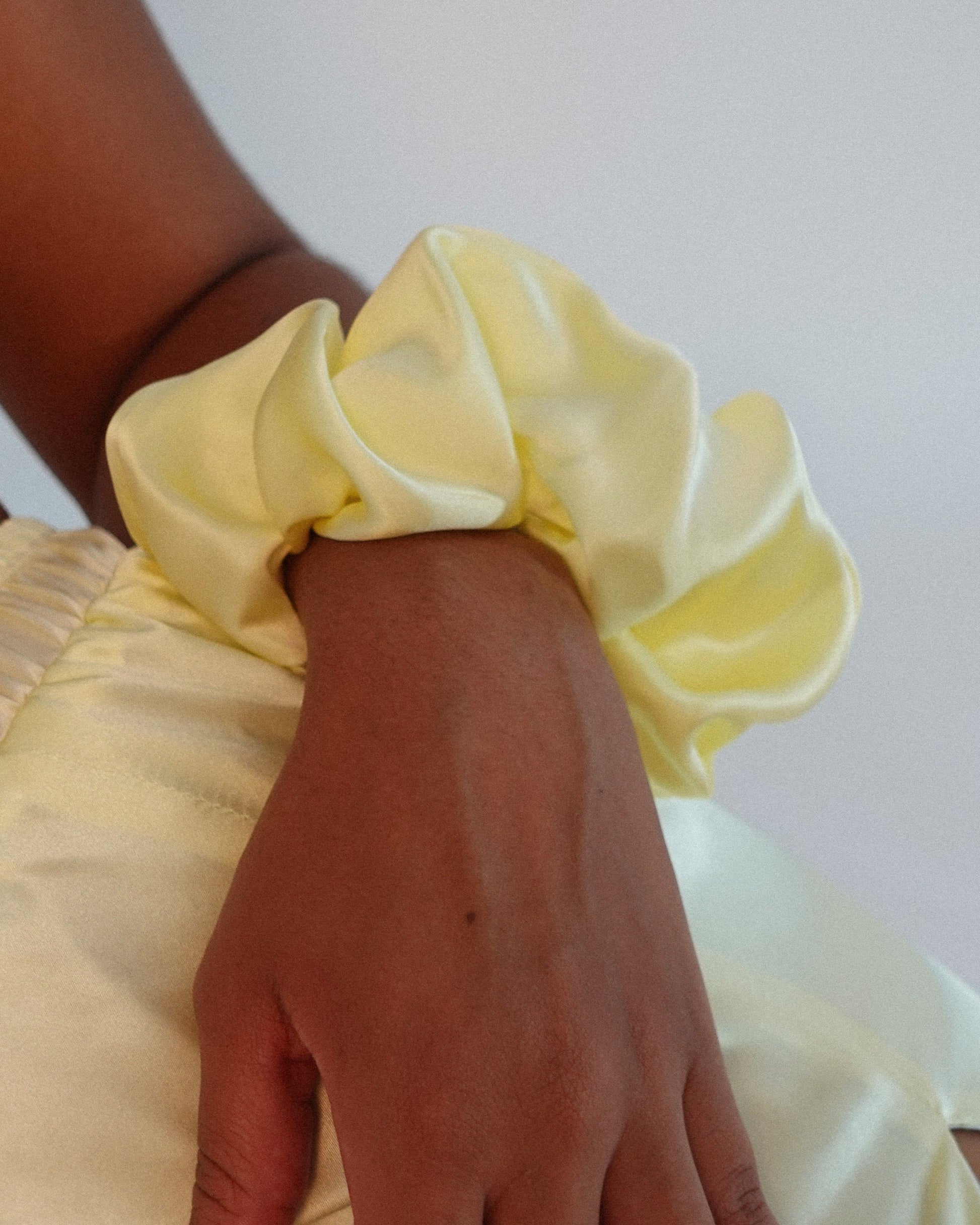 Hand wearing a yellow silk scrunchie