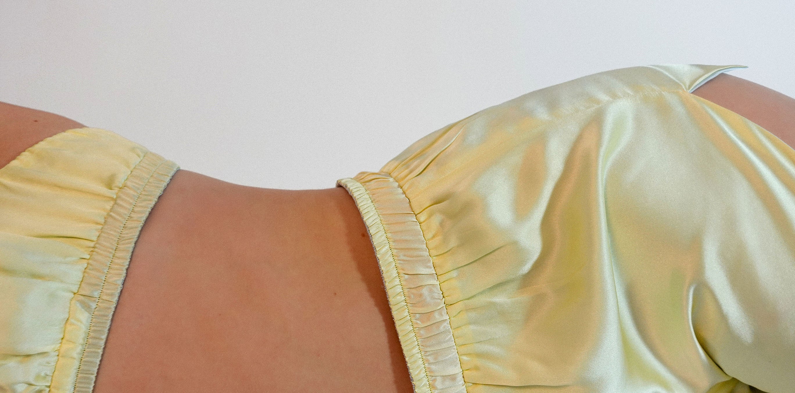 Close-up of a yellow silk satin loungewear set on a plain background