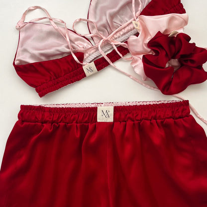 Red satin lingerie set with matching scrunchies on a white background