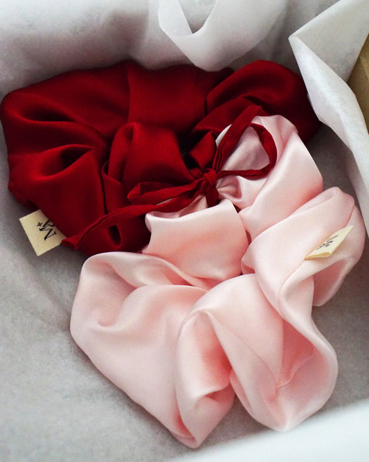 Red and pink silk scrunchies on a white background