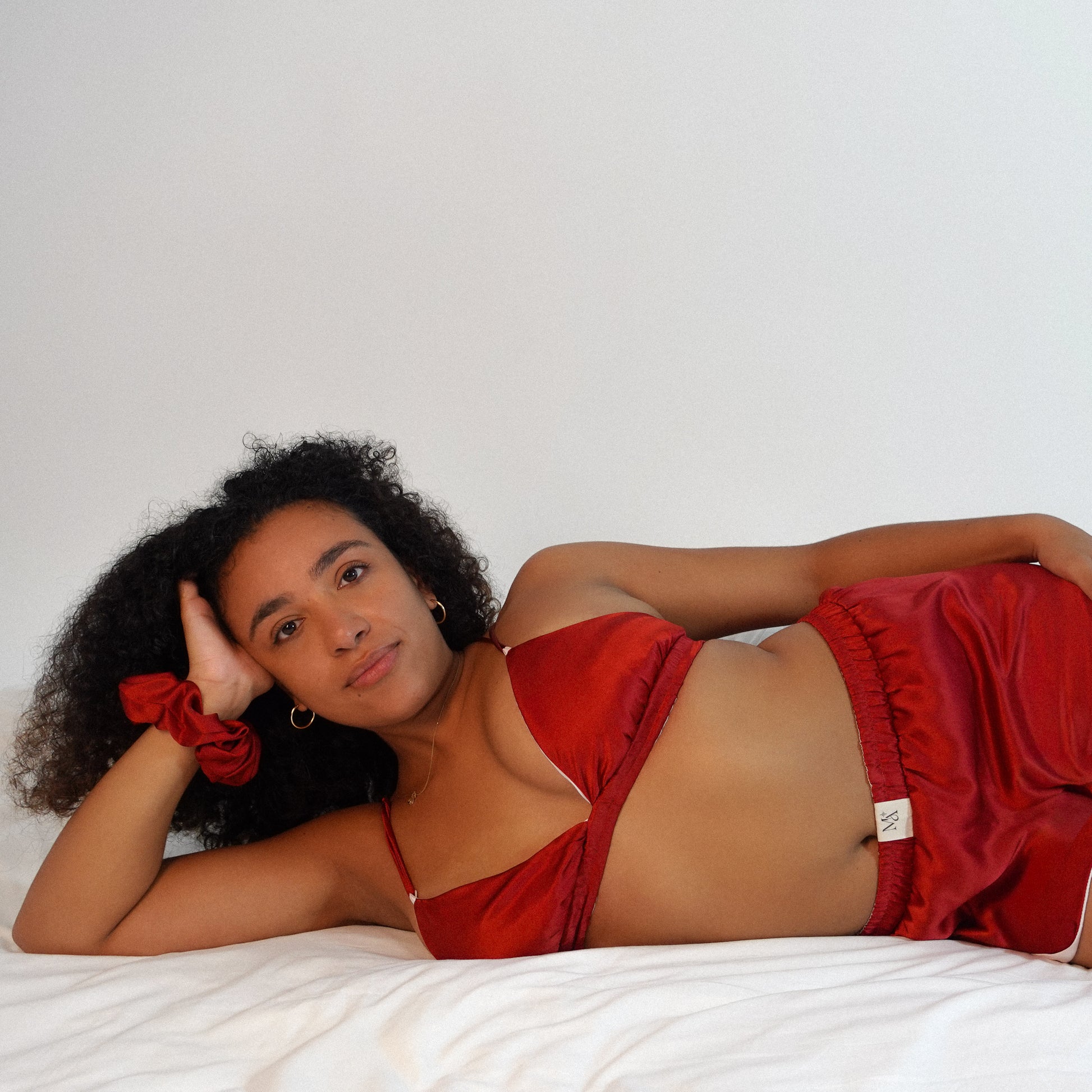 Woman wearing a red satin outfit lying on a white surface