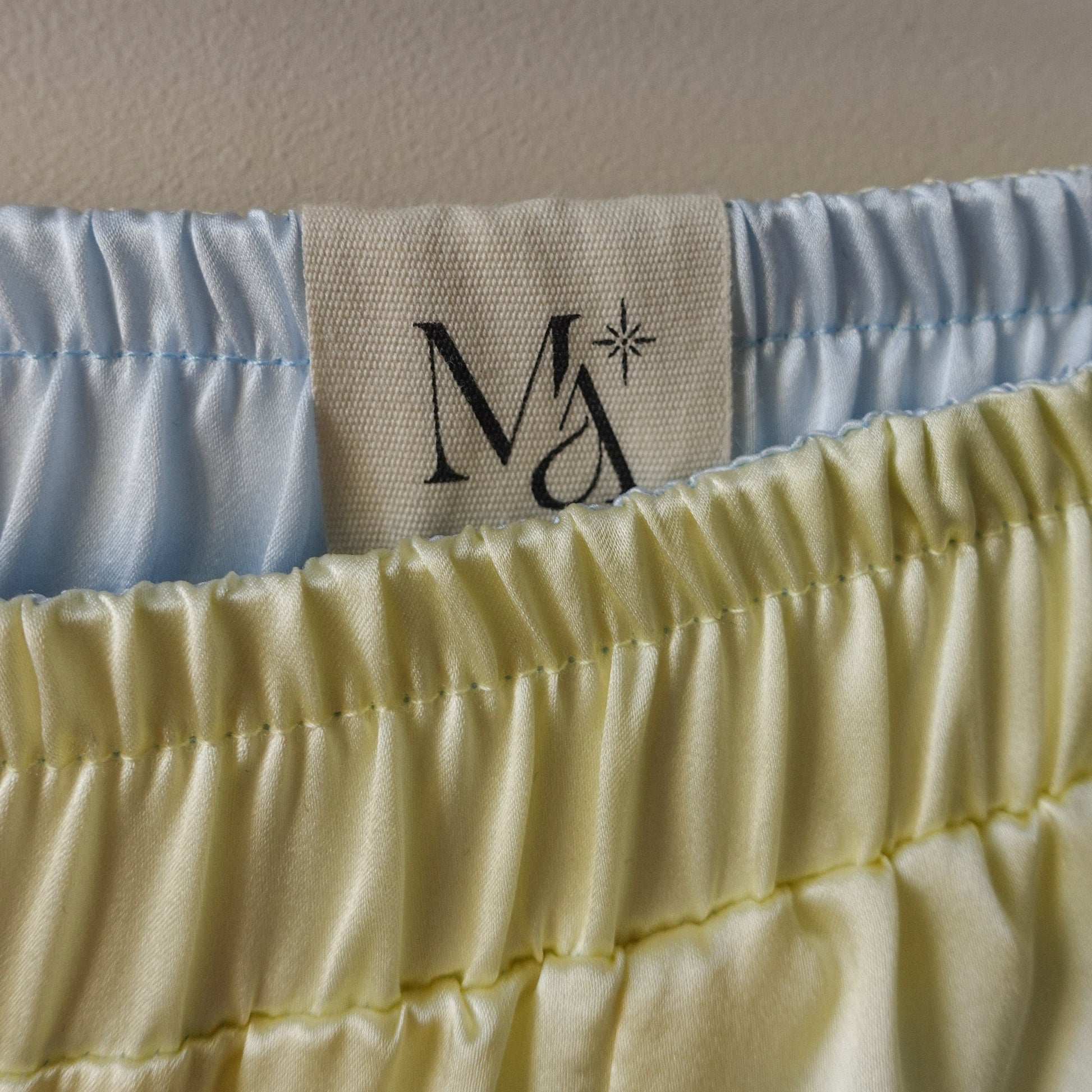 Close-up of the blue and yellow Miti reversible short, showing the Maison Manea tag and inside-out detailing
